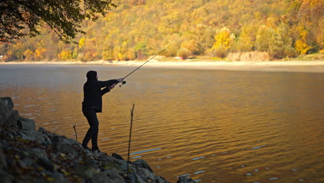 a man fishing by a lake in autumn