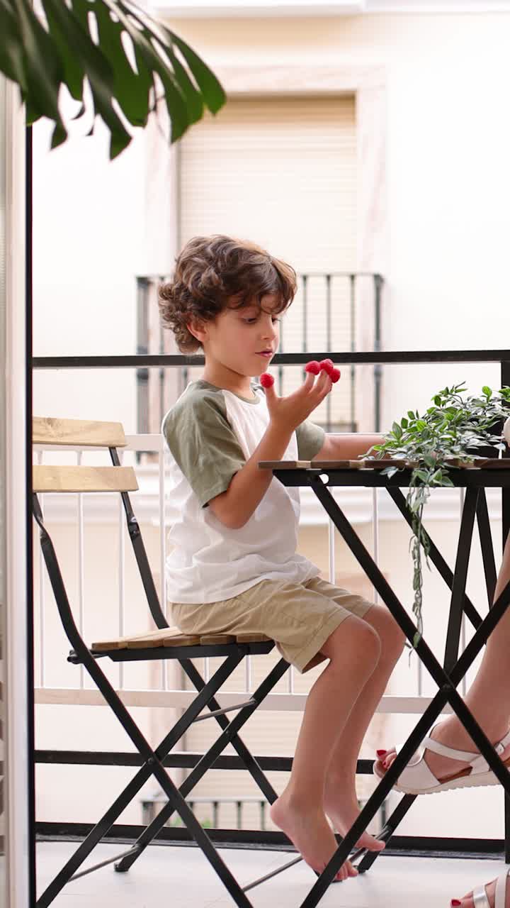 Young boy enjoying cherries on balcony