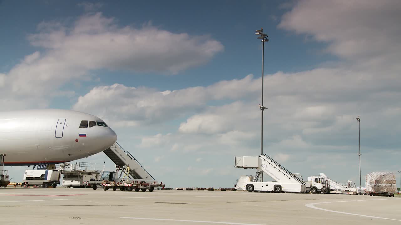 Plane at airport with mobile stairs and cargo carts
