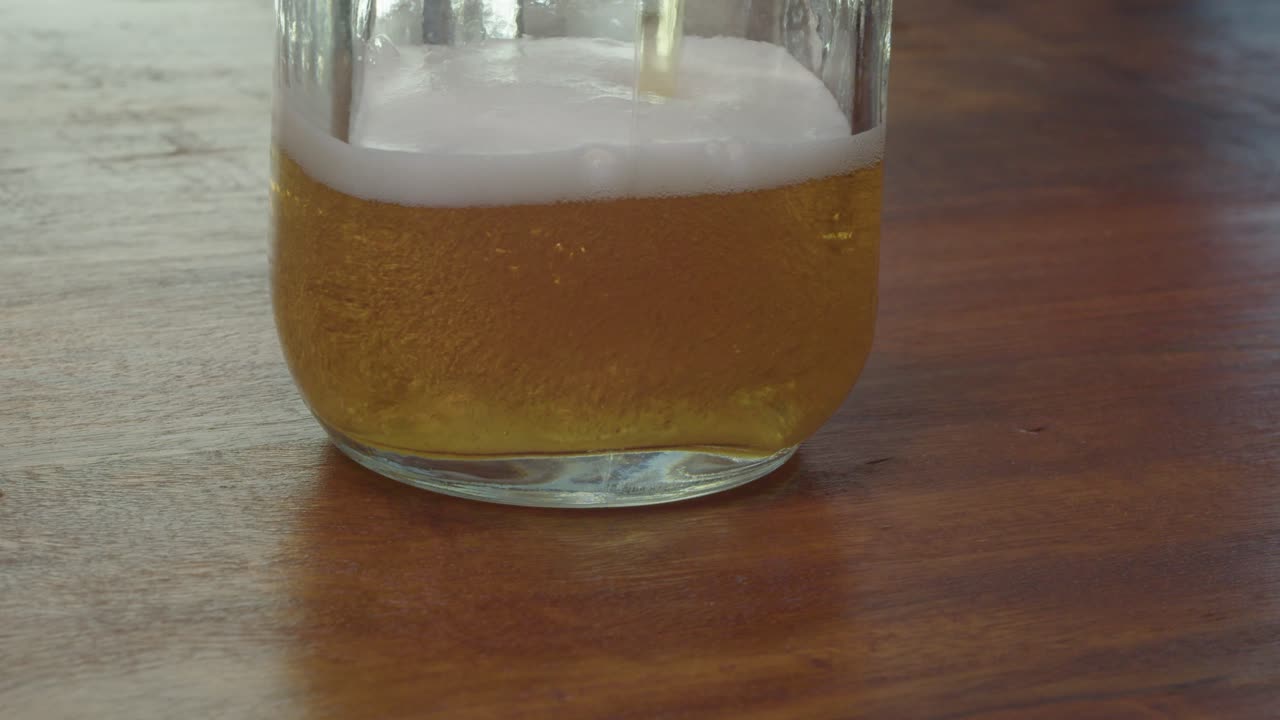 una deliciosa cerveza espumosa se vierte en un frasco de masón en la encimera, de cerca
