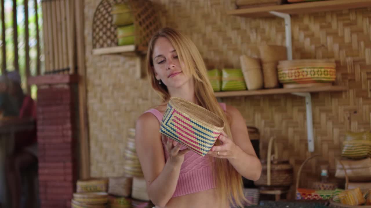 A woman holds a handcrafted bamboo souvenir engraved with the word “Bali,” showcasing the island’s rich culture, natural materials, and traditional artisan craftsmanship