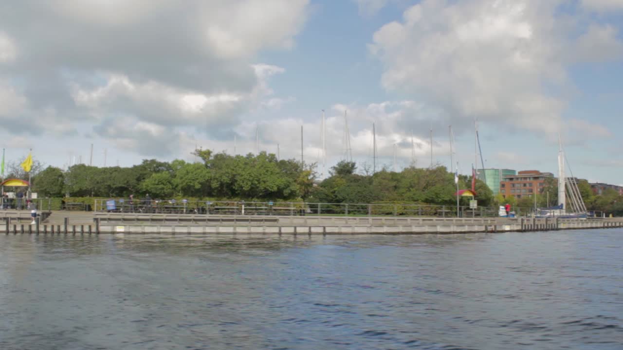 Sunny summer day at the waterfront in Copenhagen, Denmark.  Floating on the water from right to left, stopping by Mermaid statue on the rock.