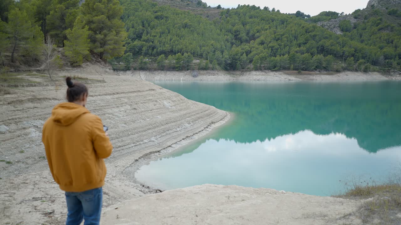 Man Standing by a Turquoise Lake with Mountains