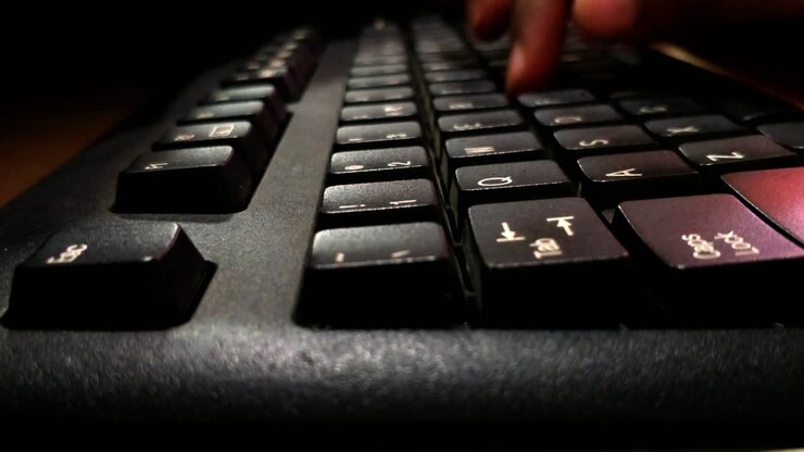 A young child typing in a keyboard of computer