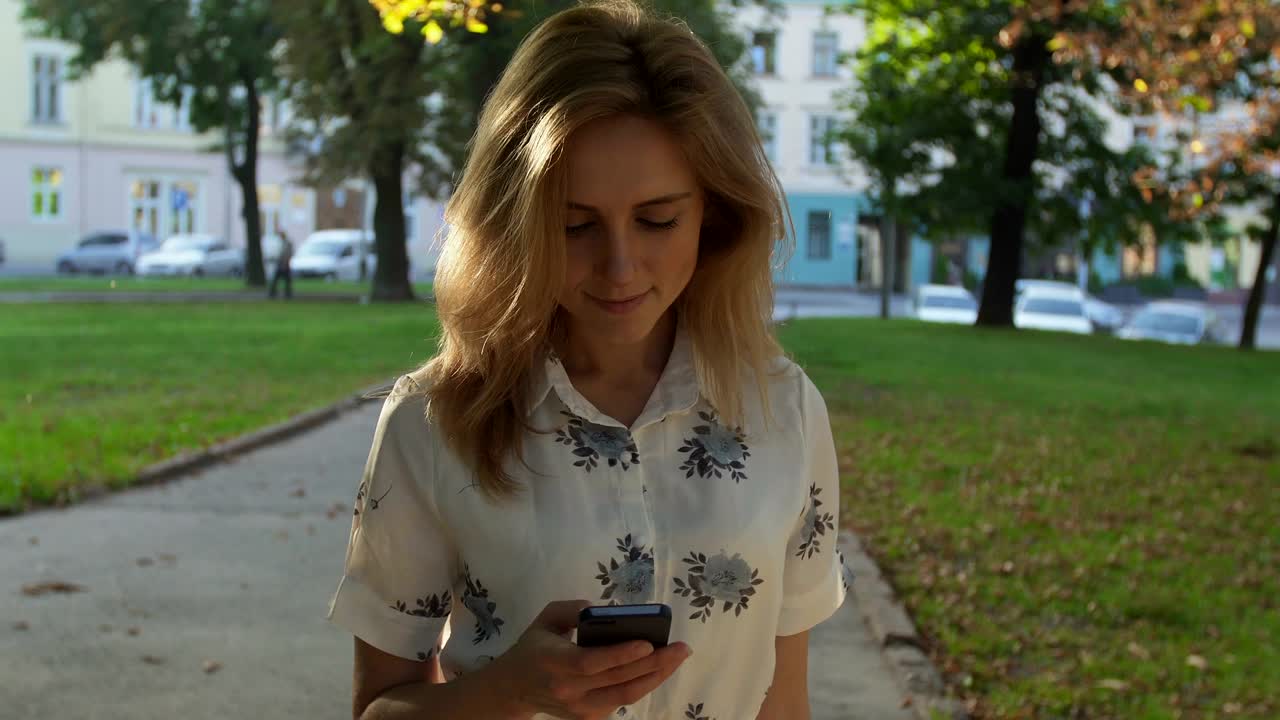 Junge Frau nutzt Smartphone im Stadtpark bei Sonnenaufgang