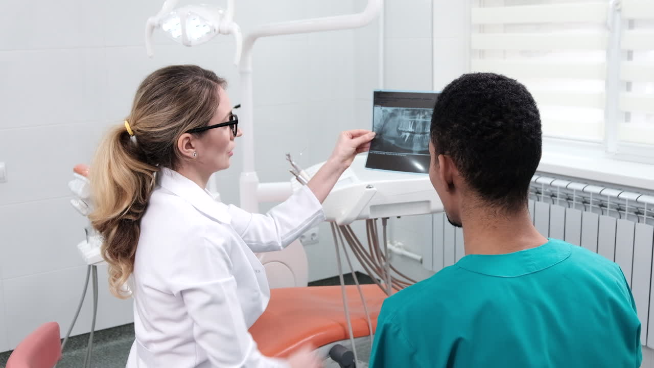 Caucasian female dentist explaining to student x-ray. Cabinet equipment on background