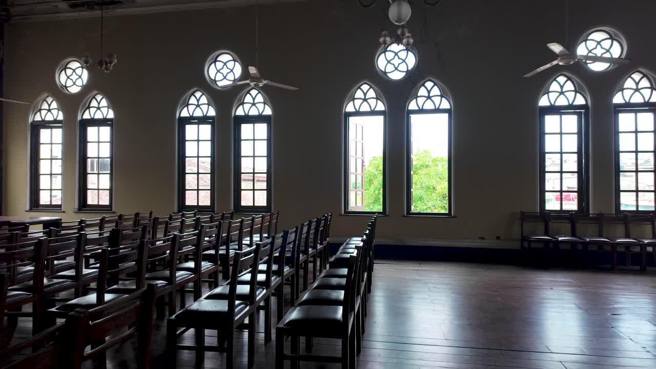 A historic lecture hall inside the old town hall in Colombo, Sri Lanka, featuring vintage chandeliers, wooden chairs, and large arched windows. The space reflects a classic architectural design.