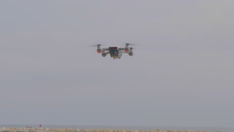 una vista de cerca de una cámara de drones voladores, luces parpadeantes y girando en la playa
