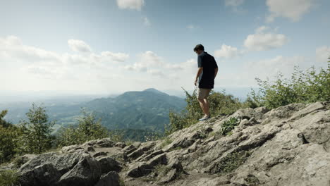 Mann-In-Dunklem-Hemd-Und-Hellen-Shorts,-Der-Zum-Aussichtspunkt-Hinuntergeht,-Um-Vom-Berg-Donačka-Gora-Ins-Tal-Zu-Sehen