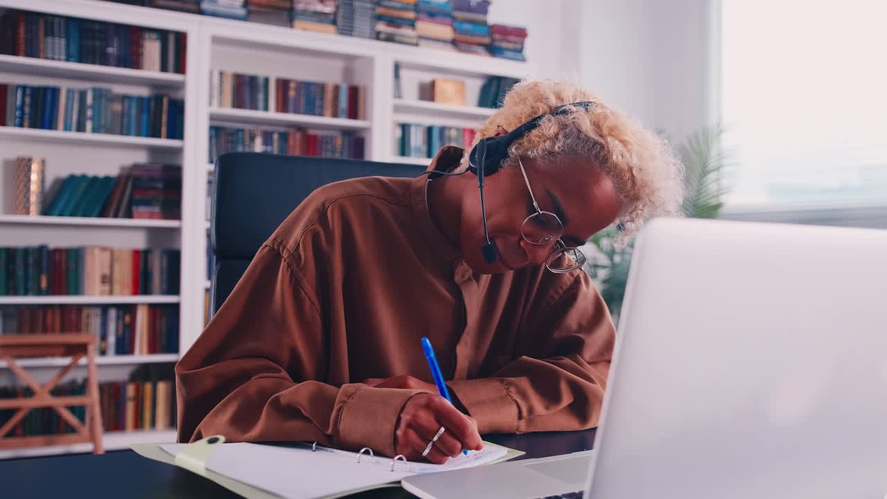 Smilende afrikansk kvinne med hodesett og mikrofon i et nettkamera videosamtalemøte