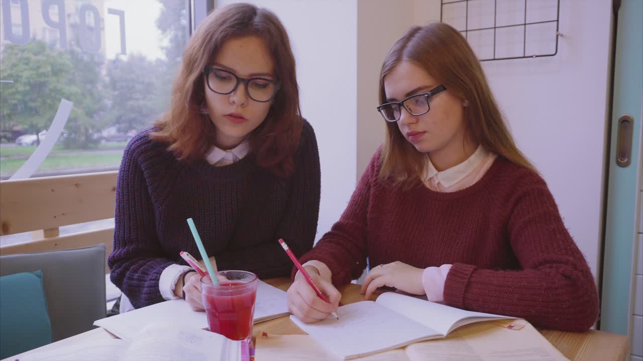 dos chicas estudiando juntas en un café