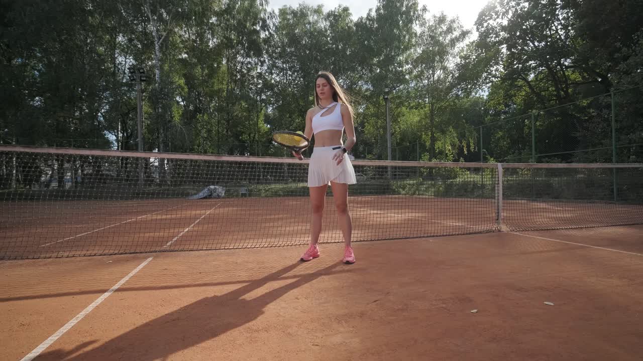 코치와 함께 야외 코트에서 테니스를 연습하는 젊은 여성. 코치는 선수가 그녀의 기술에 대해 일하면서, 운동 훈련 세션에서 그녀의 스트로크를 완성하는 동안 지침을 제공합니다.