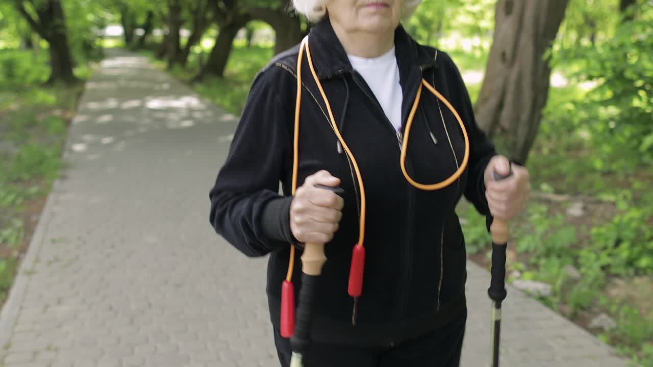 anciana activa entrenando nórdica caminando con palos de esquí en el parque