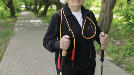 Aktive-ältere-Frau-Trainiert-Nordic-Walking-Mit-Ski-Trekkingstöcken-Im-Park