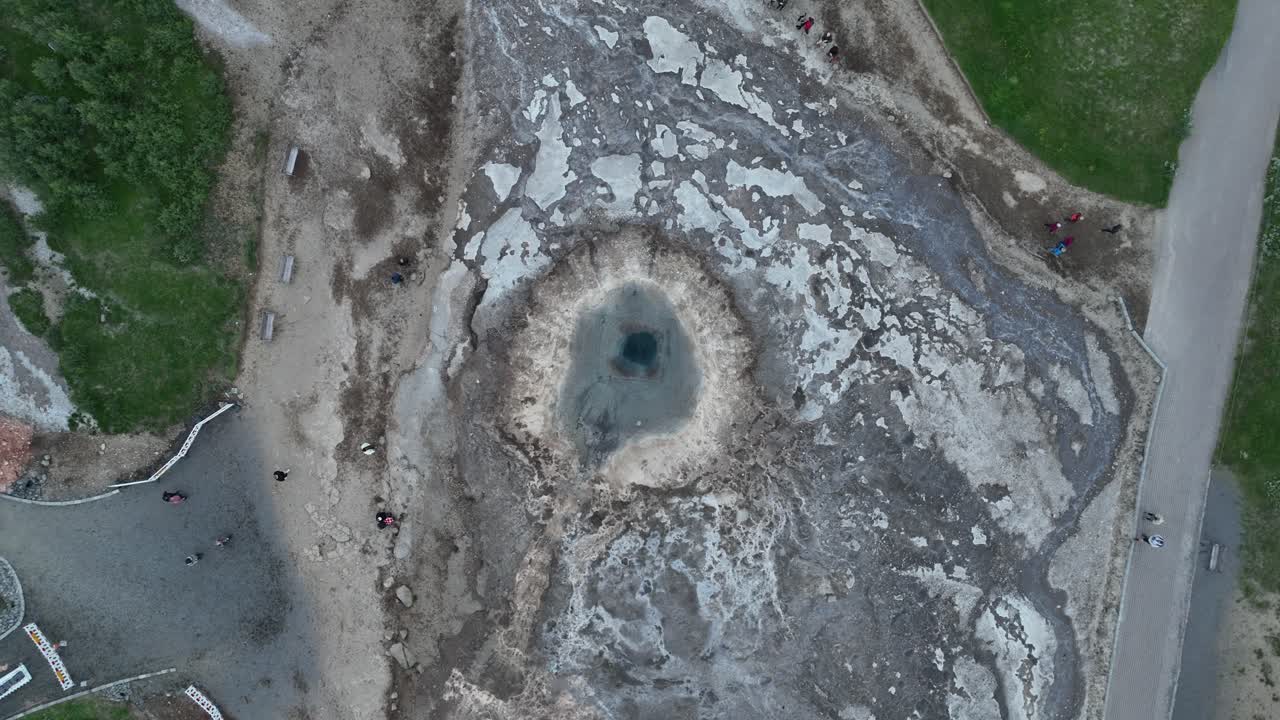 아이슬란드의 게이시르 핫 스프링 크레이터 바로 위에서 촬영된 드론은 깊은 지열 수영장, 광물 매장 및 주변 지형을 강조합니다.