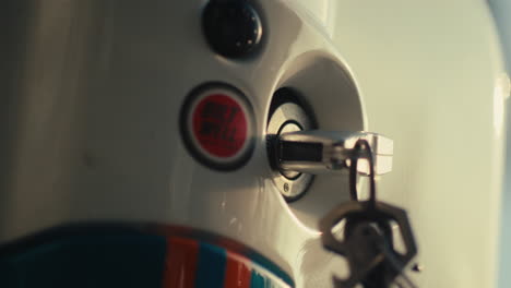 close up of a scooter ignition with a hand inserting a key