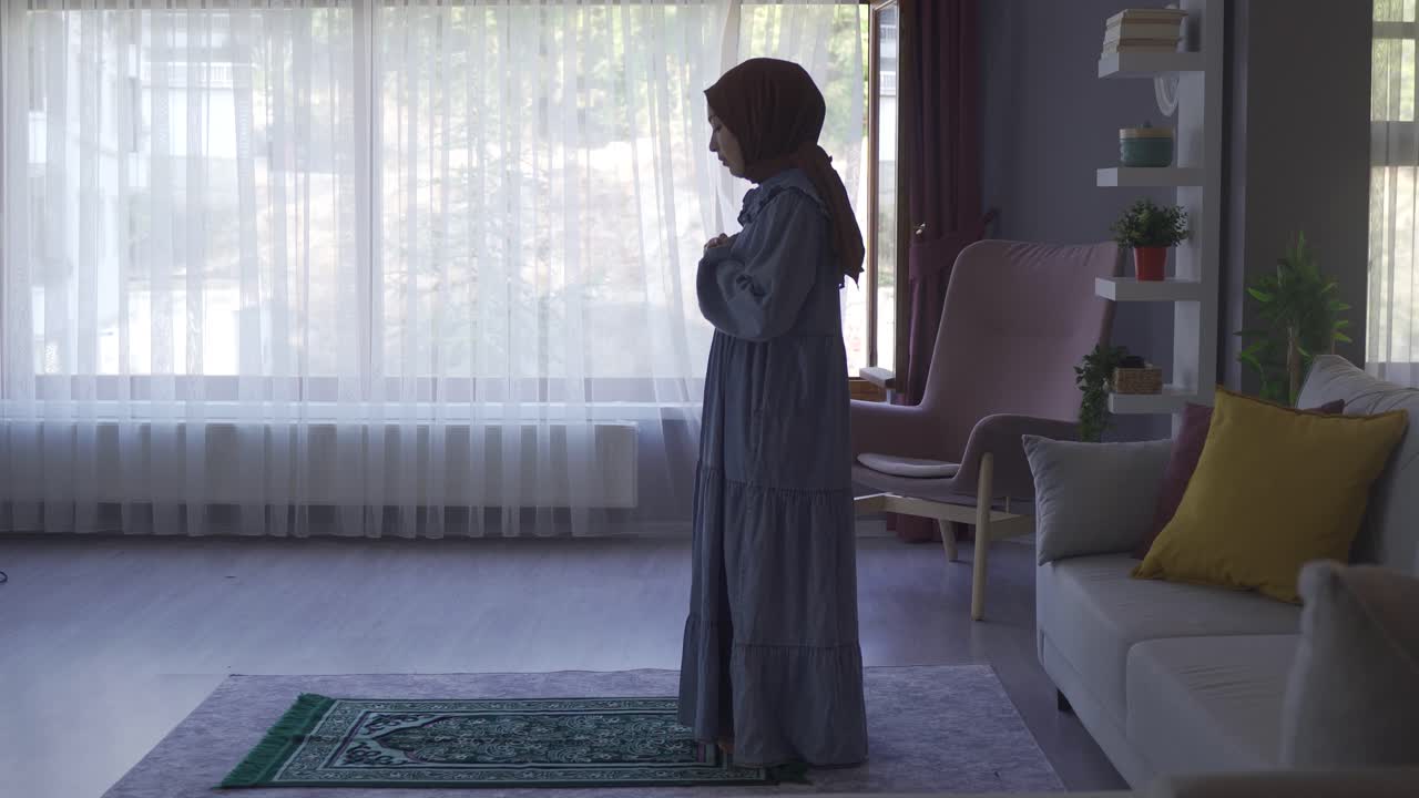 히자브를 입은 무슬림 여성이 집에서 기도하고 있습니다.