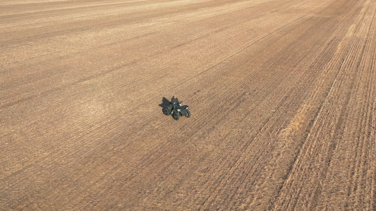 Persona guida un quad in mezzo a un campo agricolo, ripresa aerea che rivela