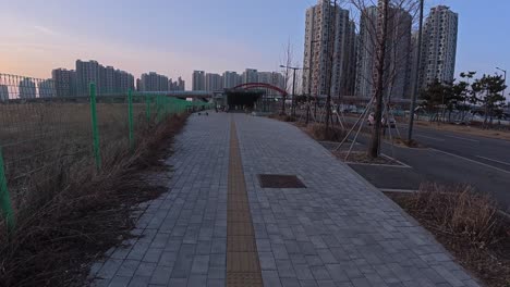 strolling on paved walkway in downtown songdo at dusk with view of apartment buildings in incheon, south korea. pov