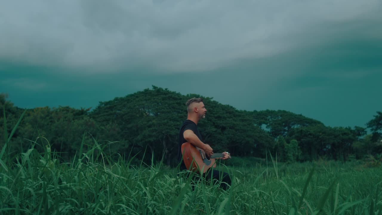 Man Playing Guitar in a Field