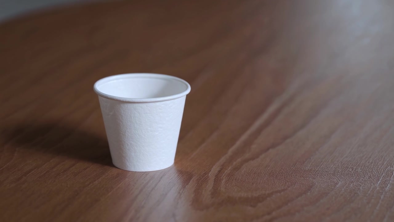 Bicchiere di carta bianco vuoto su un tavolo di legno