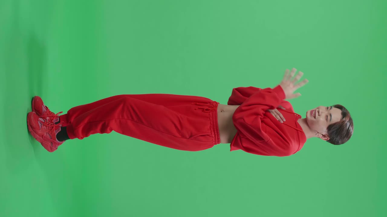 Full Body Of The Smiling Asian Transgender Male Dancing Sides While Standing In A Green Screen Studio