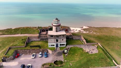 drone rises above the belle tout lighthouse situated on the edge of the beautiful seven sisters chalk cliffs