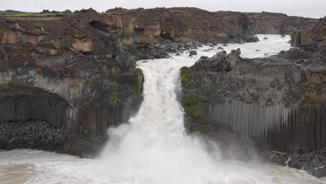 wide shot of giant aldeyjarfoss with powerful crashing water in iceland during cloudy day