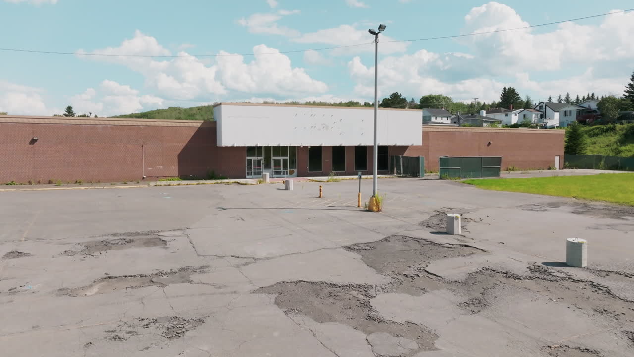 Aerial View of Abandoned Store with Overgrown Weeds and Cracked Parking Lot