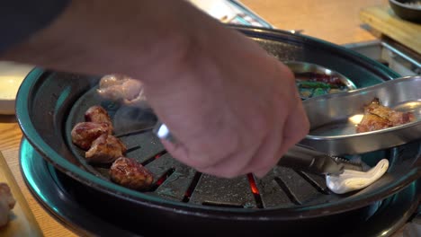 pork belly being grilled on charcoal griller in korean restaurant