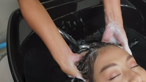 una mujer se lava el cabello en el salón.