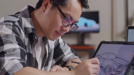 close up of asian male smiling to the camera while drawing new car design concept on a tablet in the studio with tv and computers display 3d electric car model