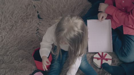 una niña rubia juega con pulseras de colores en la alfombra