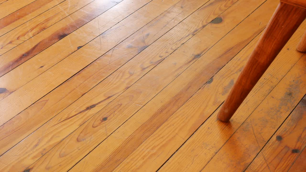 Wooden floor with scratches and a furniture leg