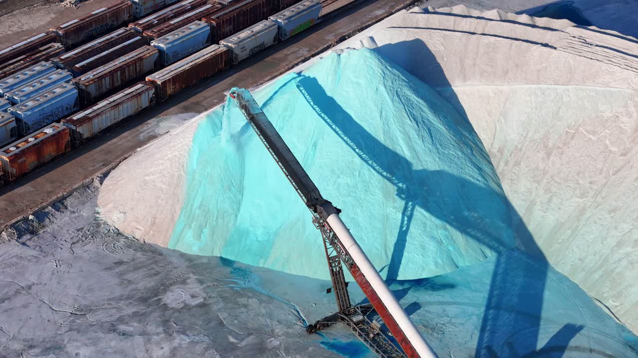 Vista aerea di un nastro trasportatore che distribuisce sale su una grande pila vicino a vagoni ferroviari presso il deposito di sale di Detroit