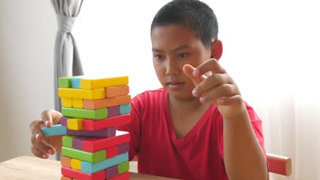 asian boy lost wood block tower game