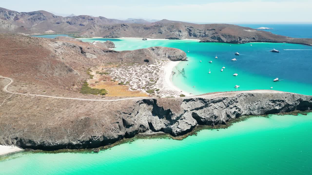 Peaceful aerial view of turquoise beach, rocky coastline, boats, and desert landscape
