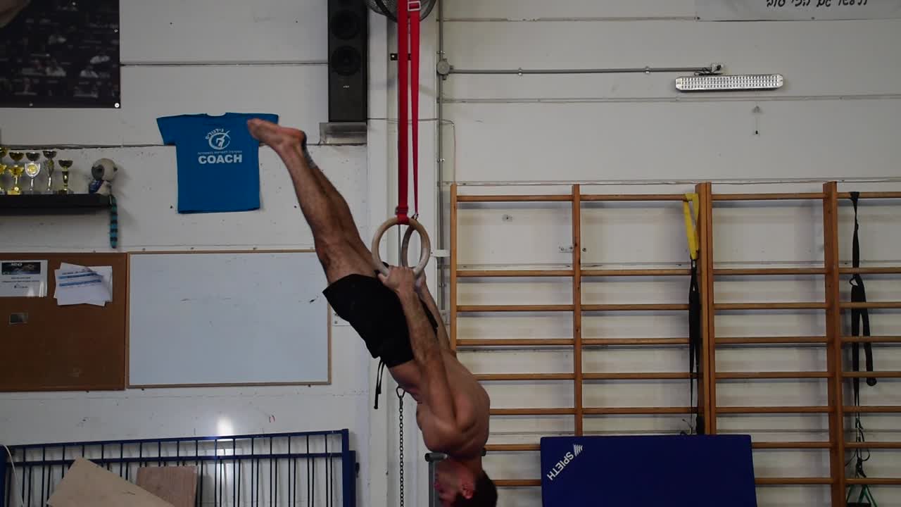 una foto fija de un tipo haciendo ejercicio en los anillos fijos de un aparato de gimnasia que es extremadamente duro en cámara lenta de 60 fps
