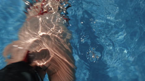 underwater beautiful young woman dives and swims, camera comes out abruptly of the water slow motion