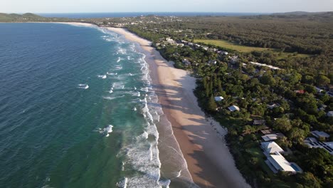 aerial view of belongil beach with lush forested coastline in byron bay, new south wales, australia.