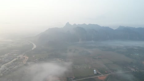 drone shot of foggy misty morning in vang vieng, the adventure capital of laos