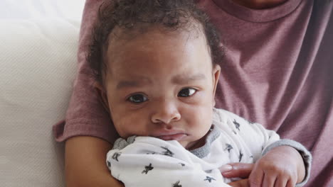 Close-up-of-newborn-baby-sitting-up-in-his-mother’s-arms,-handheld