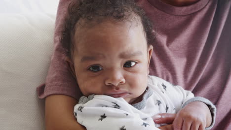 close up of newborn baby sitting up in his mother’s arms, handheld