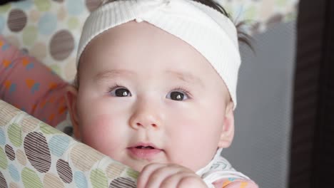 cute baby girl standing in her crib she smiles and shows her first teeth - high angle, face close up