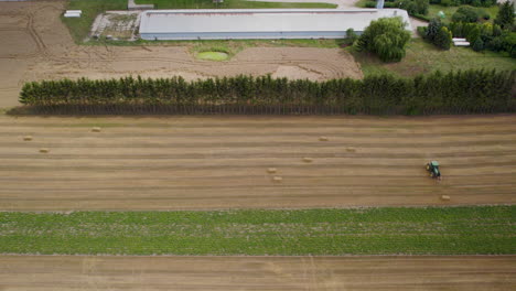 Agricultor-Trabajador-En-El-Campo,-Recogiendo-Balas-De-Heno-Cuadradas-Con-Tractor