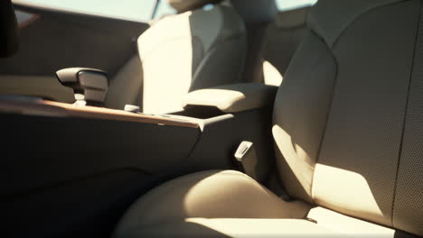 close-up of a modern car's interior with beige leather seats and sun shining through the window