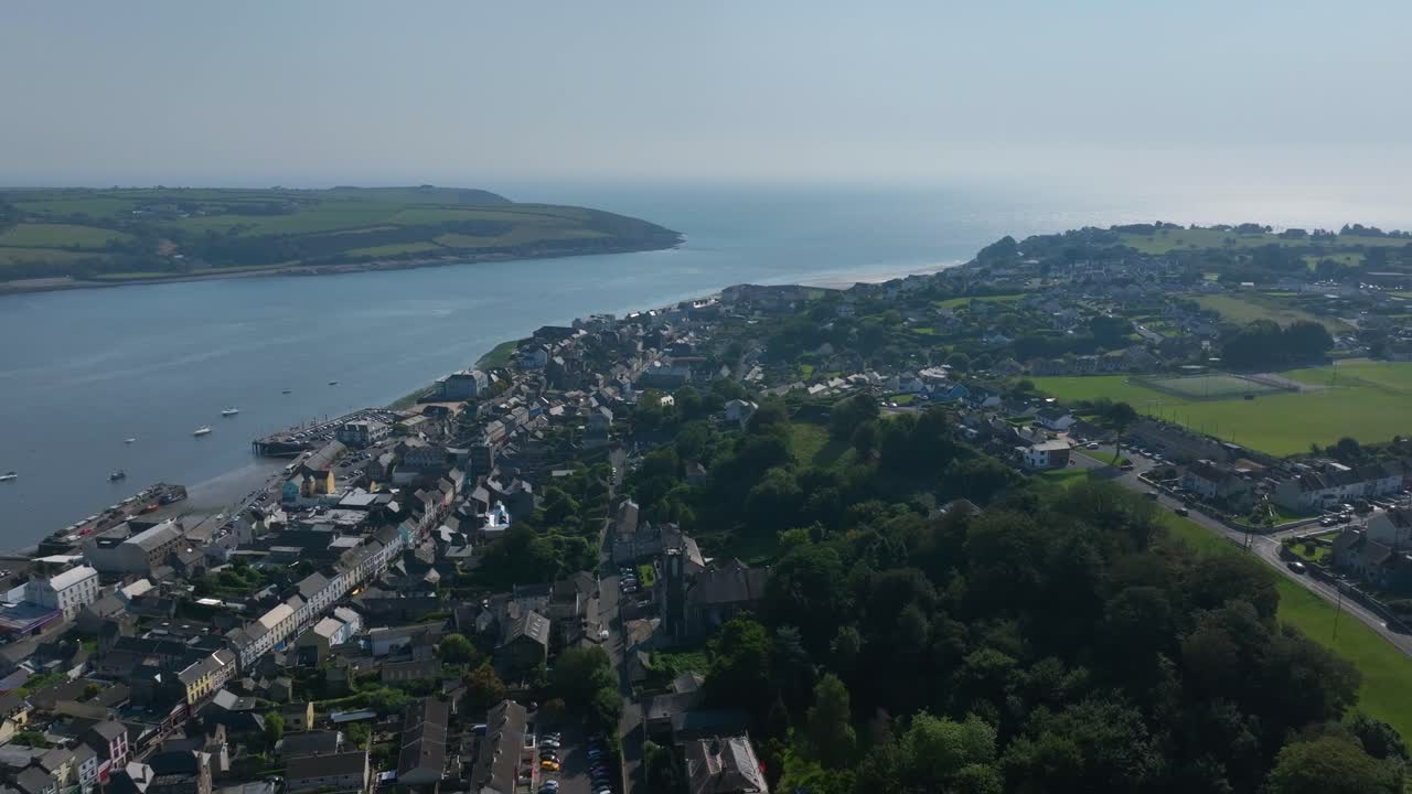 Youghal, County Cork, Ireland, September 2024. Drone panoramic aerial clockwise orbit establishing the harbour along River Blackwater with stunning views of traditional architecture and homes.