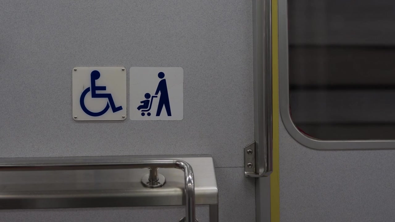 Japon treninin iç duvarında mavi tekerlekli sandalye ve bebek arabalı ebeveyn piktogramları.