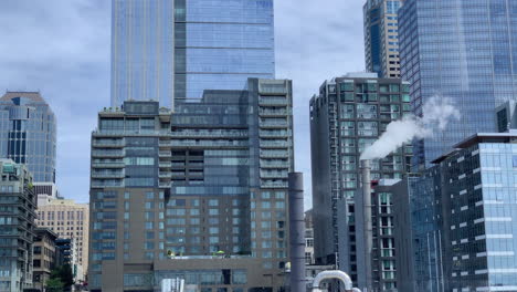 Mittlerer-Blick-Auf-Wolkenkratzer-Und-Einen-Schornstein-In-Der-Innenstadt-Von-Seattle,-Gesehen-Von-Der-Elliott-Bay