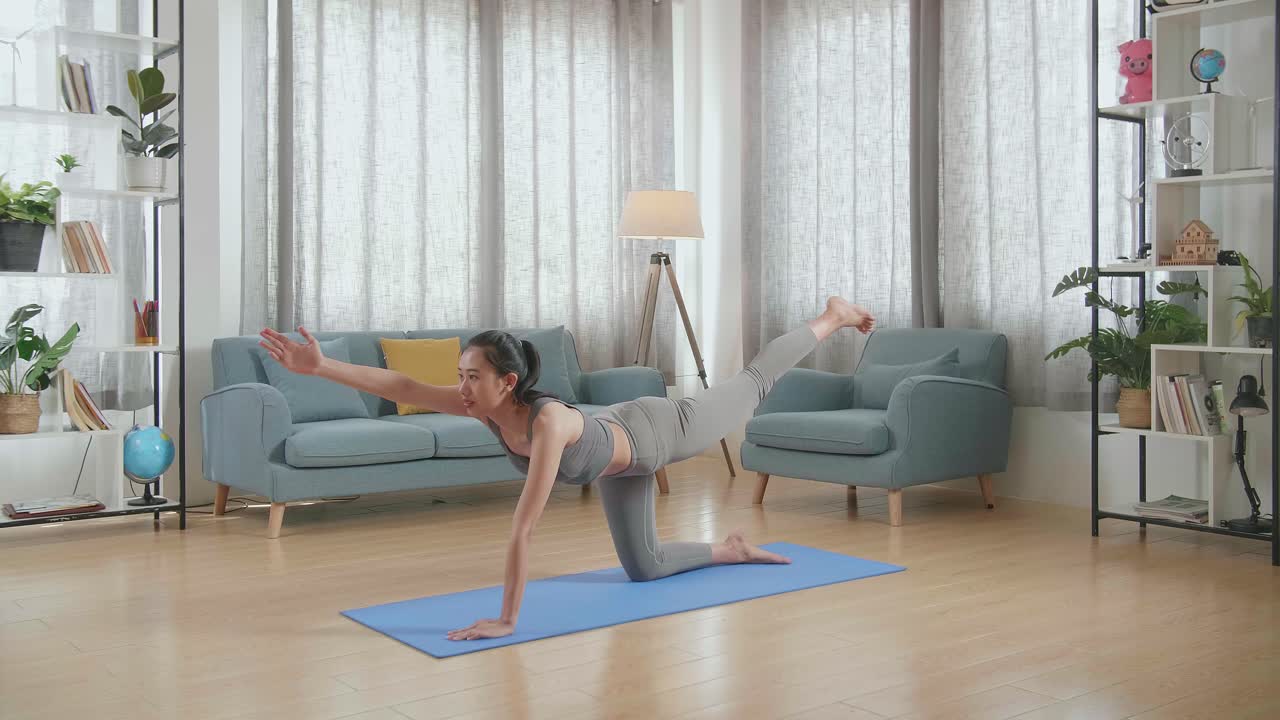 스포츠 옷을 입은 젊은 아시아 운동 여성이 집에서 매트 위에 균형 잡는 테이블 포즈에서 요가를 하고 있습니다.